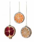 Three hanging Christmas ornaments shaped like citrus slices, including a pomegranate with deep red seeds and two orange slices with textured rinds, shown on a plain white background.